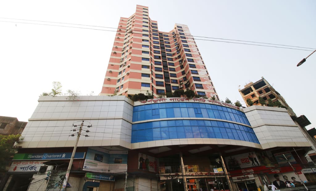Tall building with shops and blue windows.