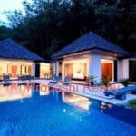 Luxury villa with illuminated pool at dusk.