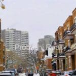 Snowy urban street with brick buildings.