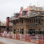 Building under construction with scaffolding and barriers.