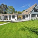 Modern house with green lawn and trees.