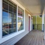 Wooden balcony with large windows and railing.