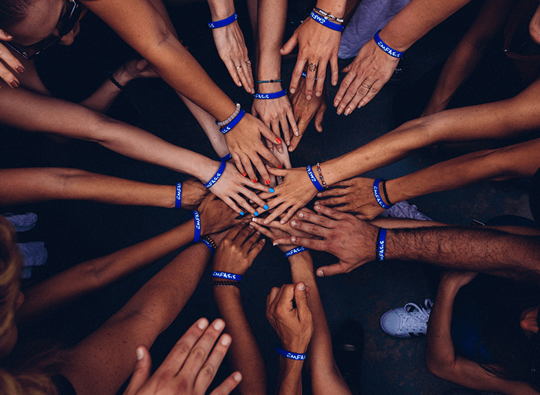 Hands with blue wristbands in a circle.