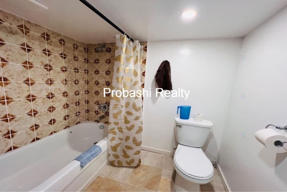 Small bathroom with tub, shower curtain, and toilet.