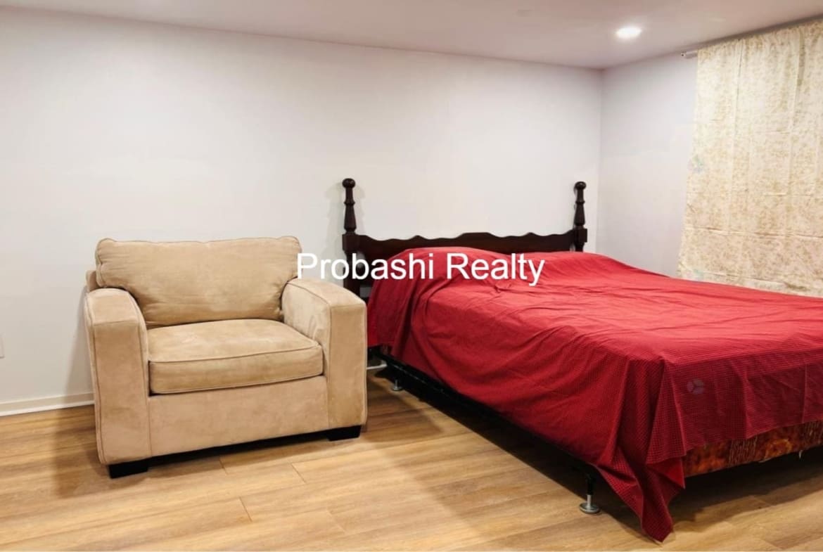 Cozy bedroom with a red bedspread and beige armchair.