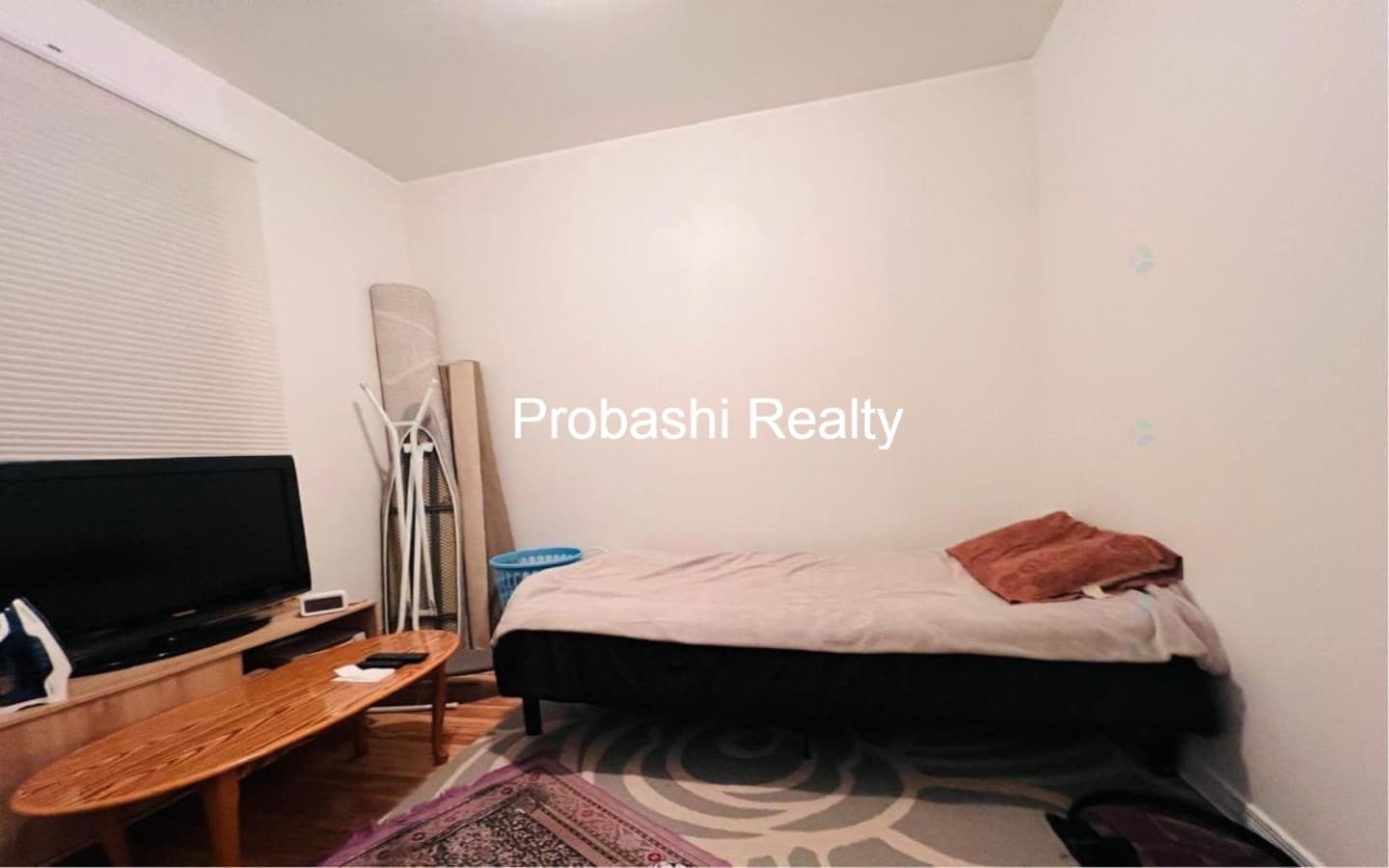 Minimalist bedroom with a bed, TV, and simple decor.