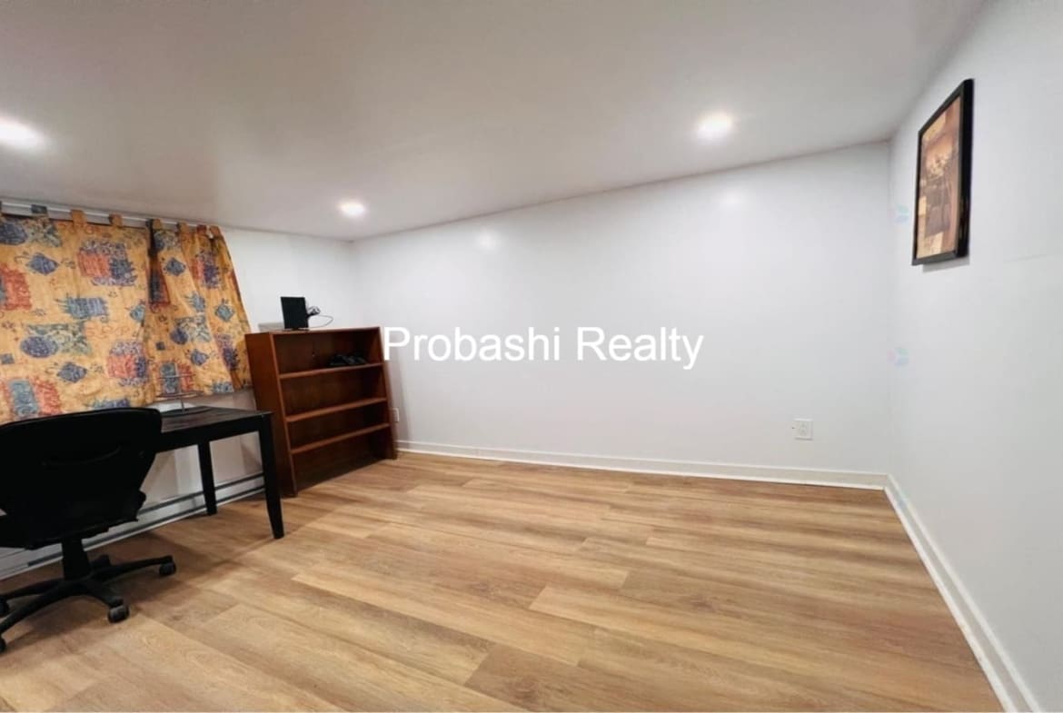 Empty room with wooden flooring and white walls.