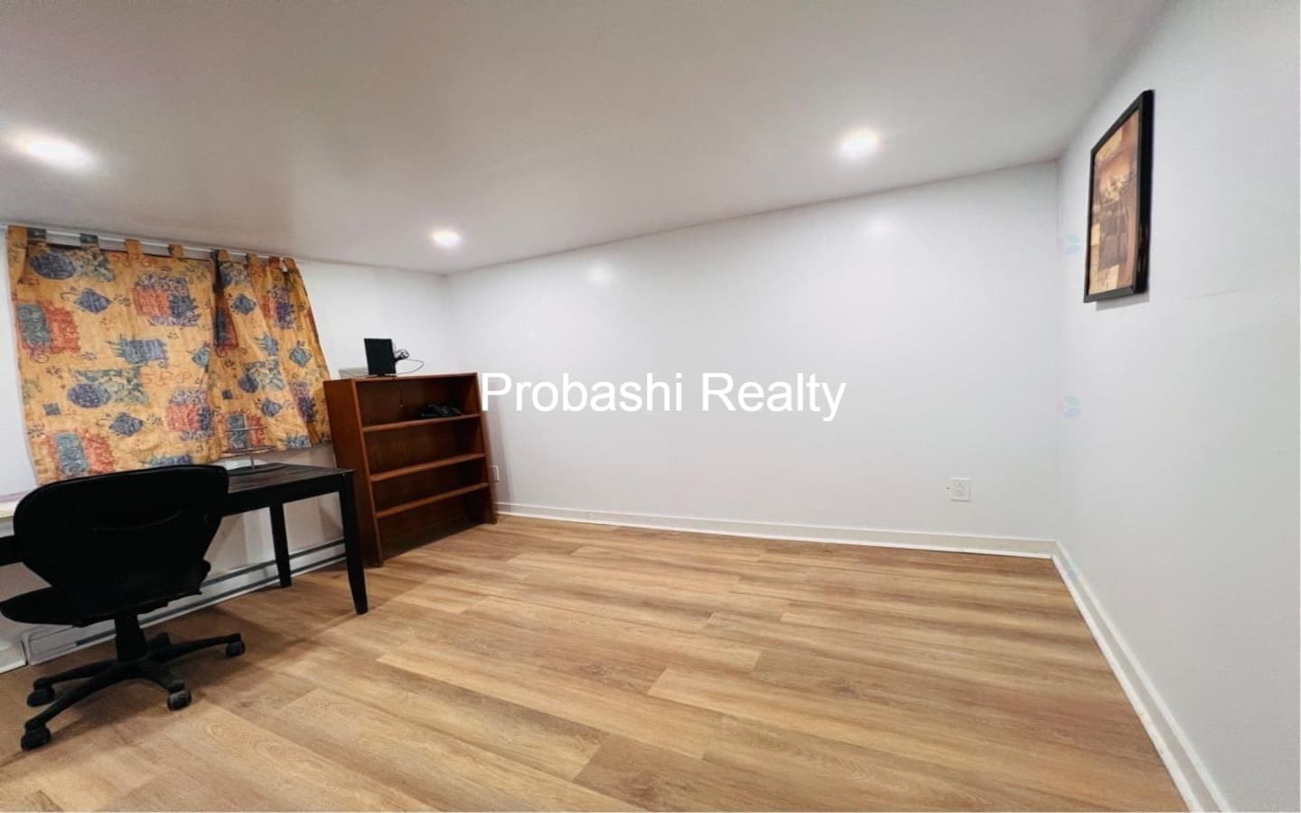 Empty room with wooden flooring and white walls.