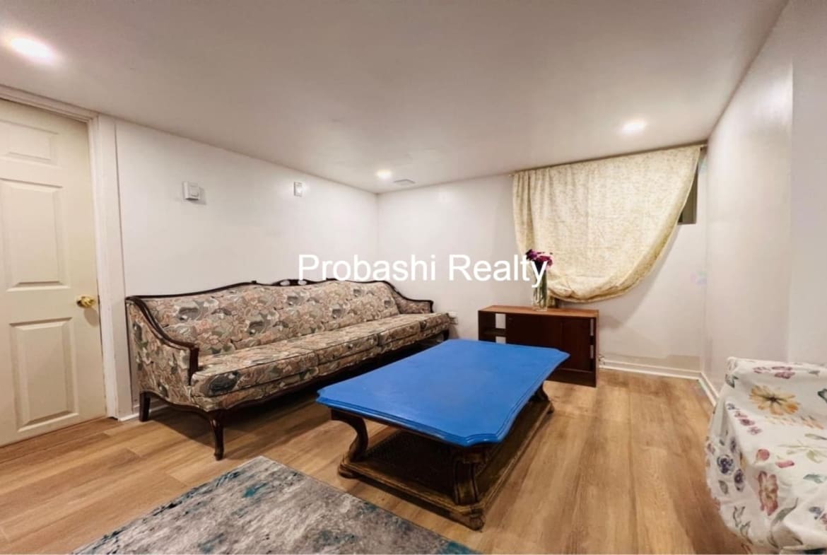 Cozy living room with vintage sofa and blue ottoman on wooden floor.