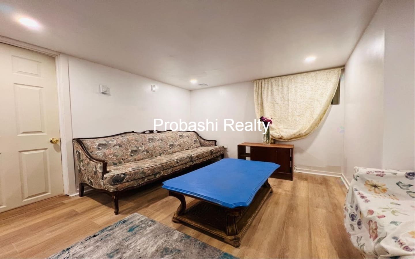 Cozy living room with vintage sofa and blue ottoman on wooden floor.