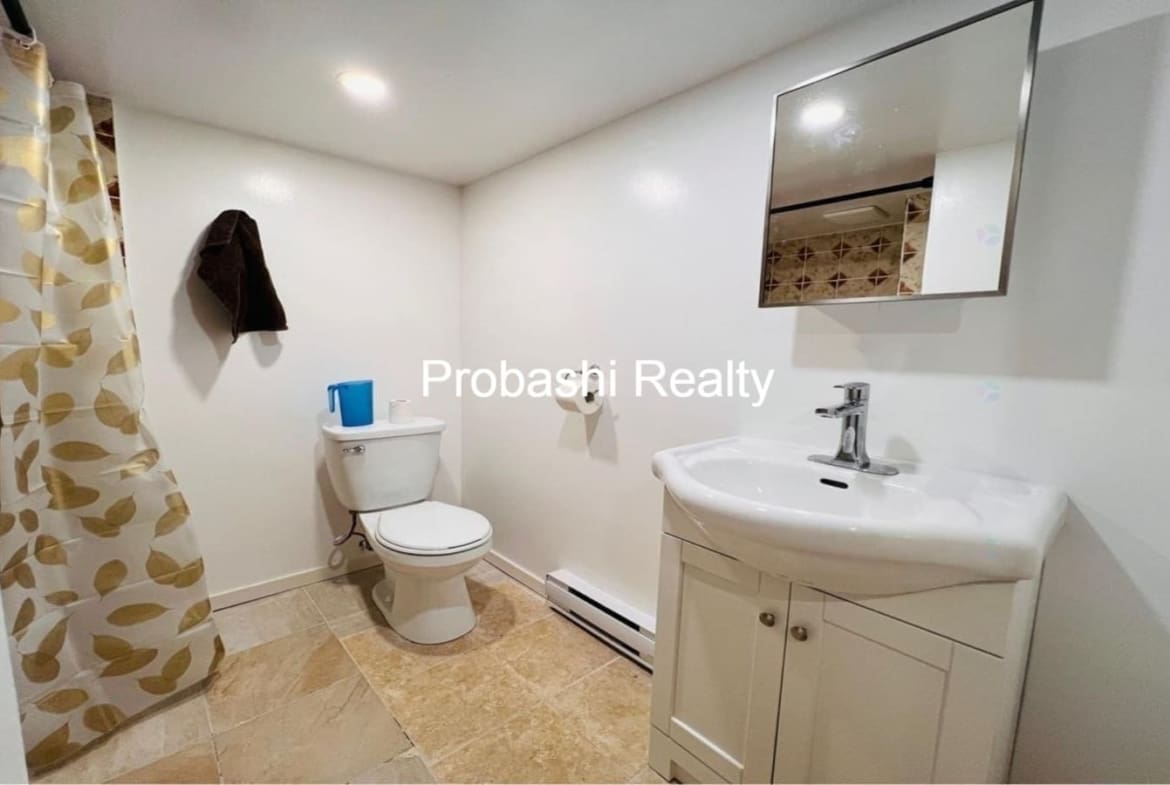 Clean bathroom with toilet, sink, and mirror.